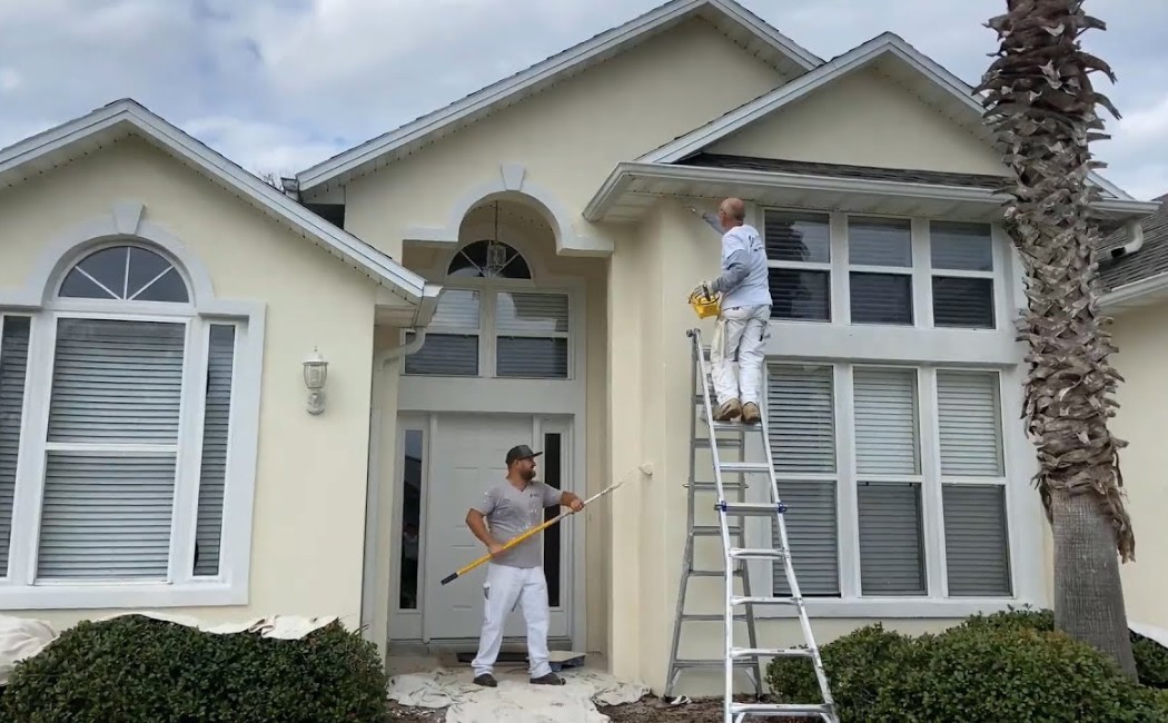 Professional exterior painting service with painters applying fresh paint to a modern residential home exterior.