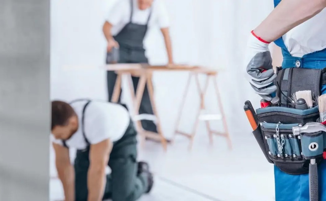Handyman Experts Renovating Residential Interiors. Handyman company experts performing home renovation and repair work with tool belts and equipment in a residential interior.