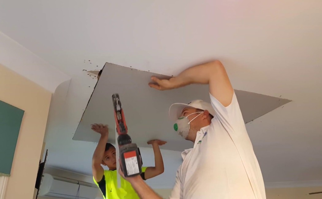 Drywall Installation for Ceiling Renovation. Drywall Installation professionals installing a ceiling drywall panel during a residential interior renovation project.