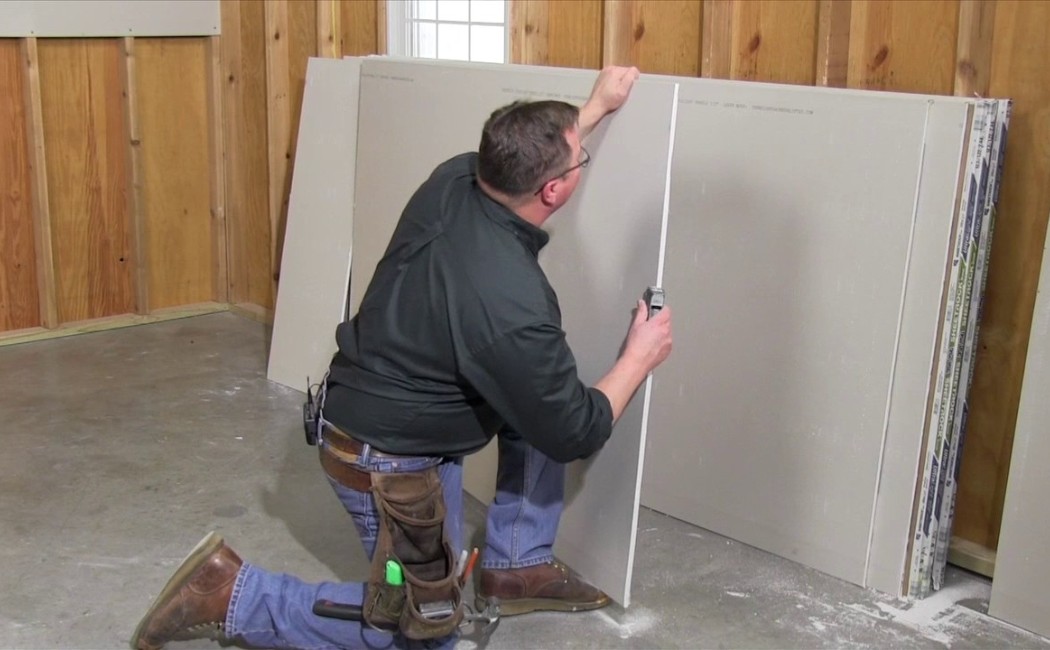 Drywall Installation contractor measuring and cutting a drywall sheet for precise fitting during interior wall construction.
