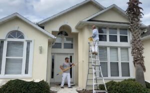 Professional exterior painting service with painters using rollers and a ladder to paint the exterior walls of a modern residential home.